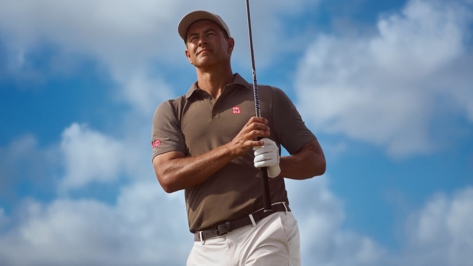professional golfer Adam Scott wearing a dark grey UNIQLO polo shirt and cap and off white trousers