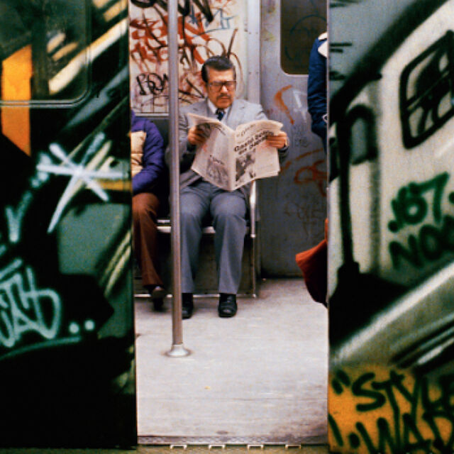 Photograph of man in train with graffiti by Martha Cooper