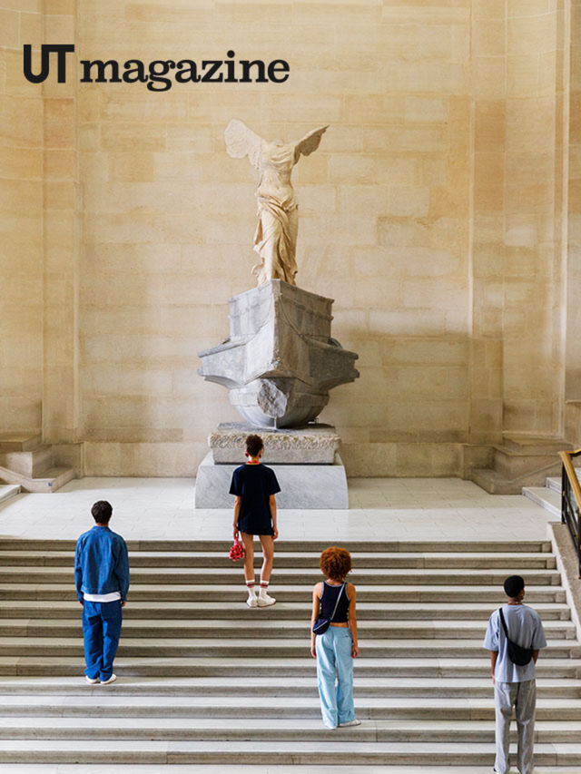 three people walking up stairs to see one statue attached to original rock the statue was on