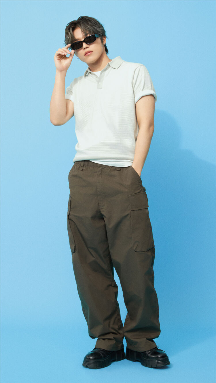 A full-body outfit image of PARK JEONG WOO standing in a white polo shirt and olive cargo pants, wearing NARROW TYPE Rectangle Sunglasses characterized by their thick side temples.