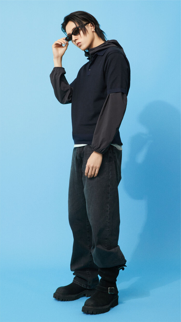 A full-body outfit image of HARUTO striking a pose with one hand on his frames, wearing trendy Narrow Sunglasses paired with a sporty, black-based layered style.