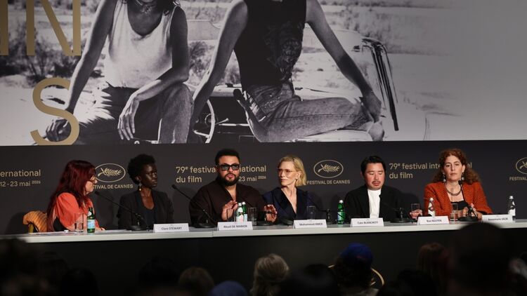 The press conference scenery of the Displacement Film Fund (DFF) Second Cycle at the 79th Cannes Film Festival. From left to right: Clare Stewart, Akuol de Mabior, Mohammed Amer, Cate Blanchett, Bao Nguyen, and Annemarie Jacir are seated side by side at the table with microphones.