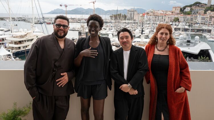 The four selected directors for the Displacement Film Fund Second Cycle smiling together against the backdrop of Cannes harbor and numerous yachts. From left: Mohammed Amer, Akuol de Mabior, Bao Nguyen, and Annemarie Jacir.