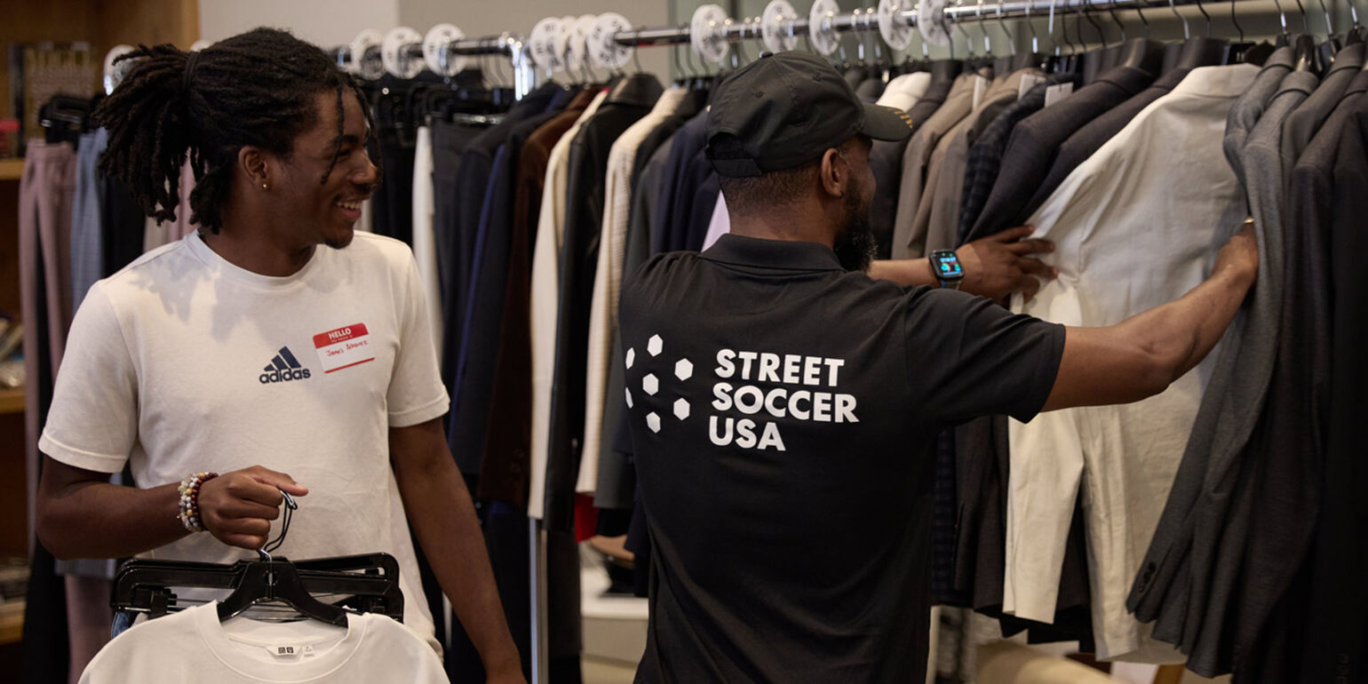 Two people looking through a clothing rack