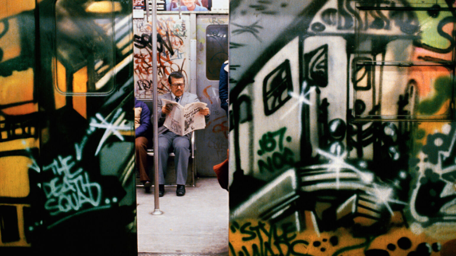 Photograph of man in train with graffiti by Martha Cooper