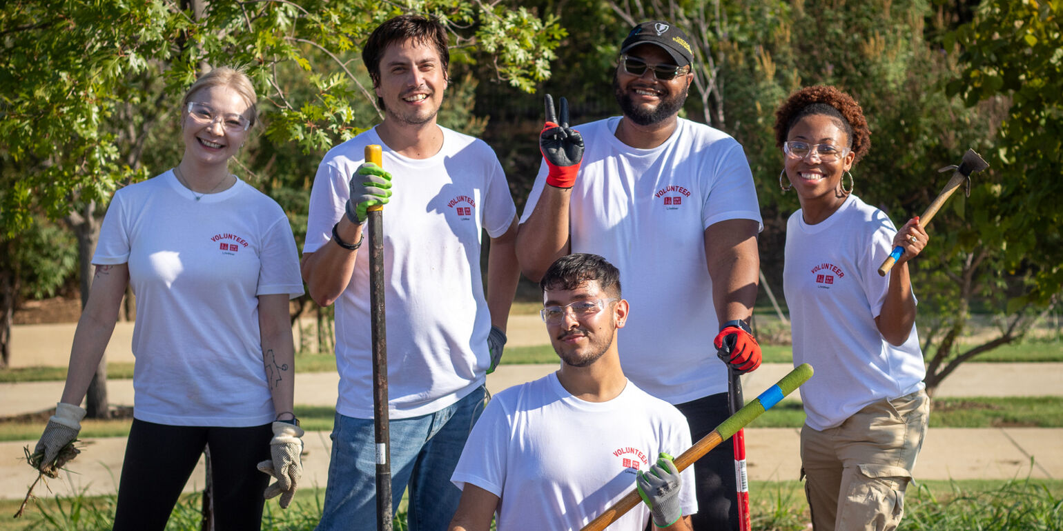 four volunteers holding outdoors at a park