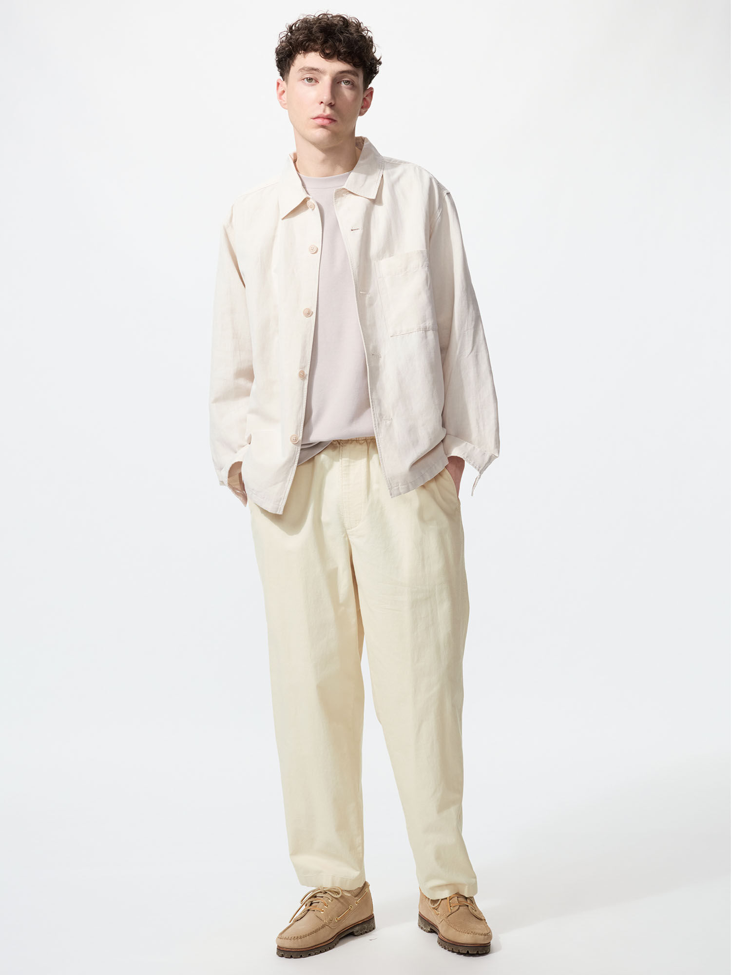 A model facing the front. Wearing a tucked in light pink shirt, a Cotton Linen Shirt Jacket in natural beige, and Linen Blend Easy Ankle Pants in natural as well.