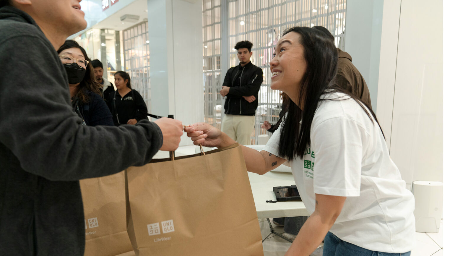 Woman giving bag of UNIQLO products to someone