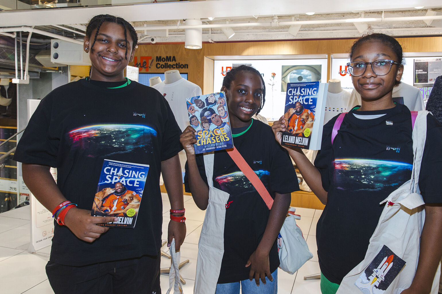 Young children sharing their copies of books by Leland Melvin and Peace For All graphic t-shirts