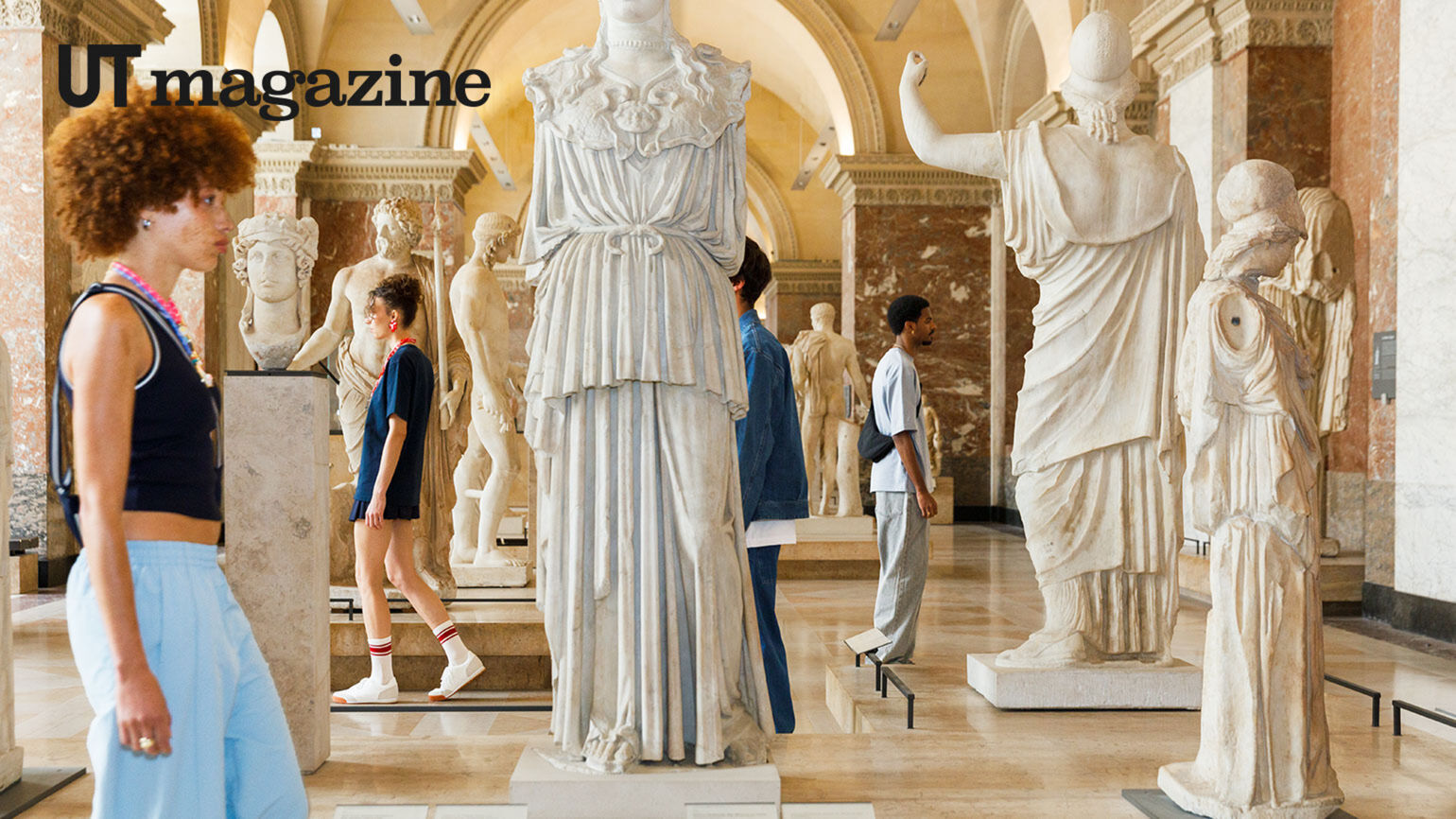 people passing through museum interior in an exhibit with large statues