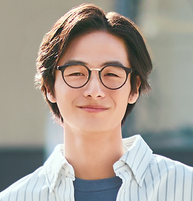 A portrait of a man wearing Boston-style combination sunglasses, smiling freshly at the camera in soft, natural light.